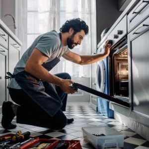 home-appliance-repair-man-fixing-oven-in-modern-kitchen-photo