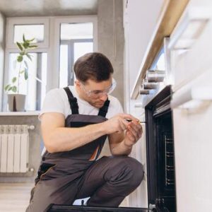 plumber-repairing-oven-in-modern-kitchen-photo